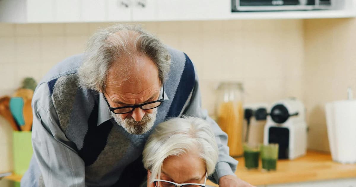 Older couple sitting together and reading documents at home, representing Social Security COLA planning and household budgeting.